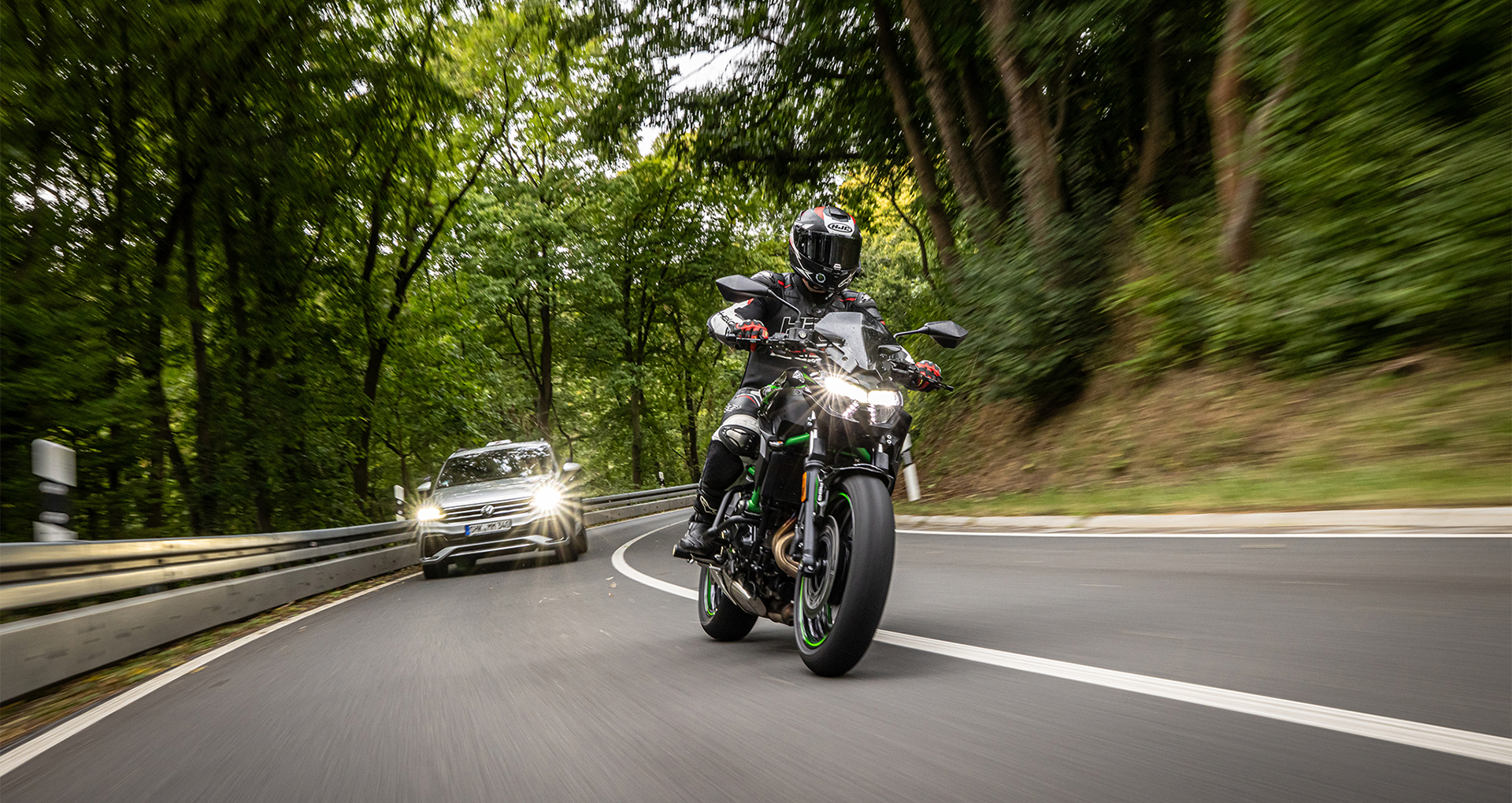 Motoradschüler und Fahrlehrer im Auto auf der Landstraße in einer Kurve